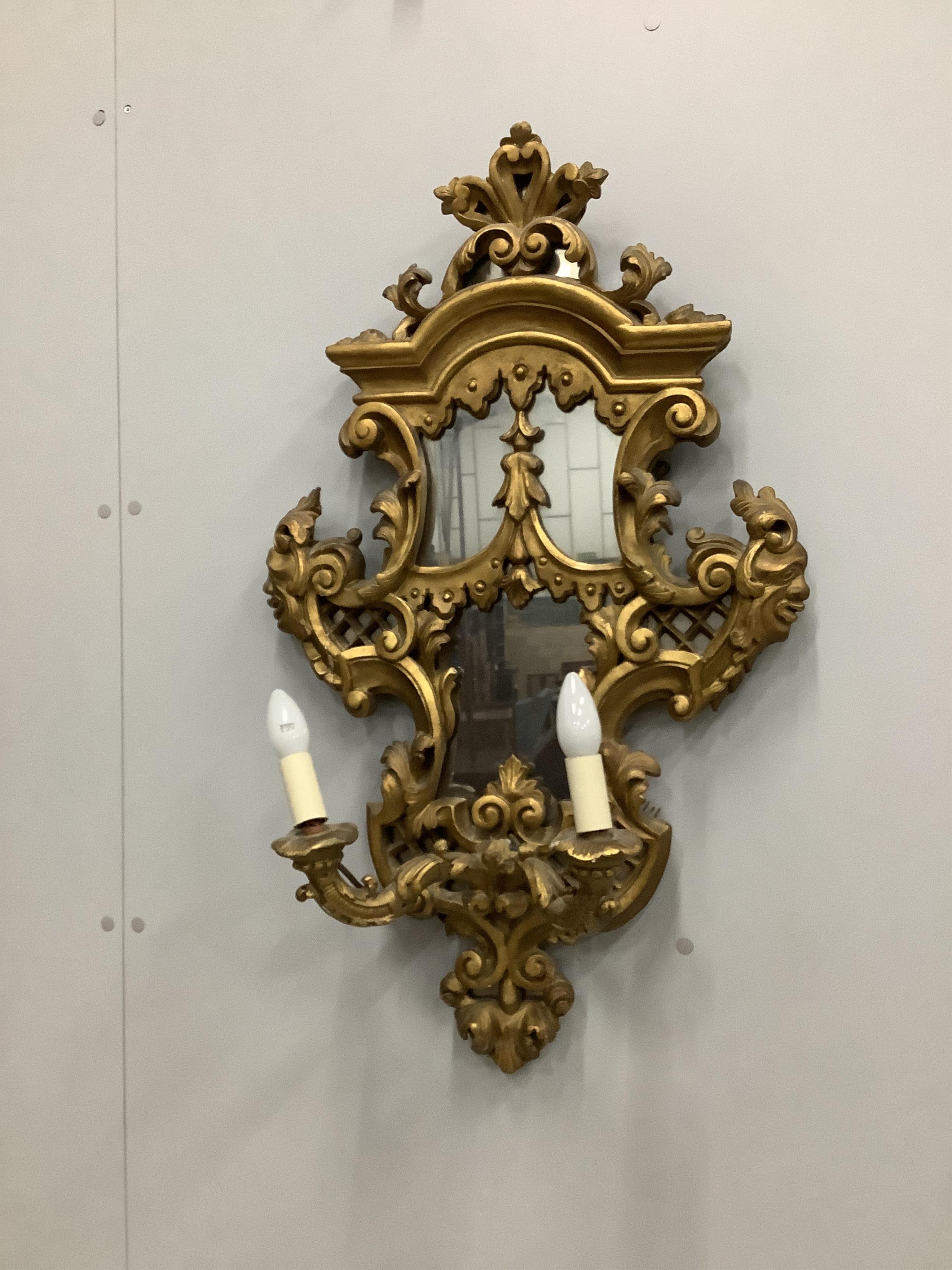 A pair of Italian style carved giltwood and composition two branch girandoles, width 52cm, height 86cm. Condition - poor